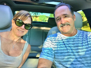 Smiling couple sitting inside car before road trip