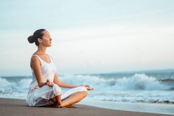 woman on the beach doing yoga near san clemente with ocean in the background