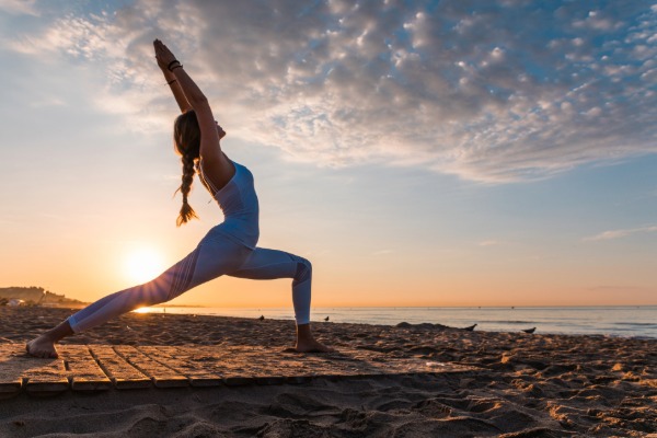 woman practicing yoga on the beach during sunset near san clemente
